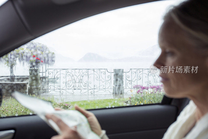 女人在车里休息，看着地图，在湖边