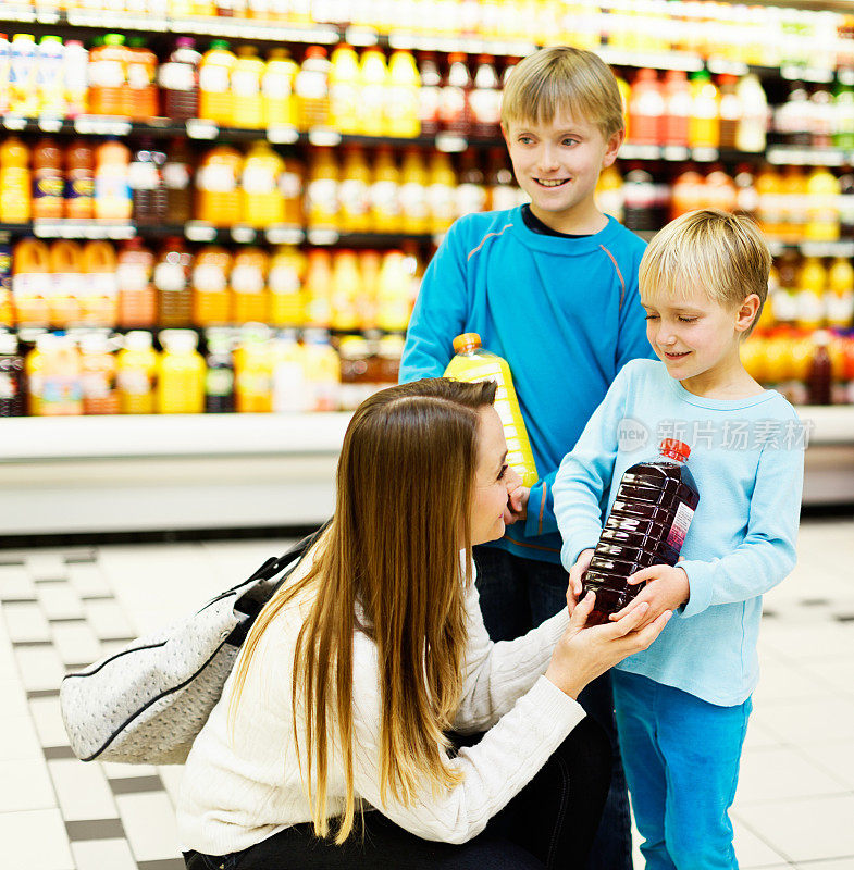 快乐的孩子们帮助妈妈在超市买果汁