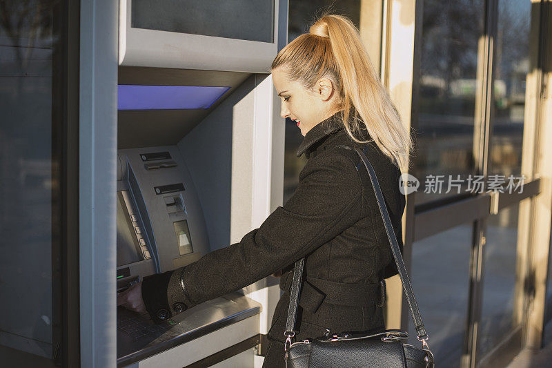 一个女商人使用自动取款机的侧面图