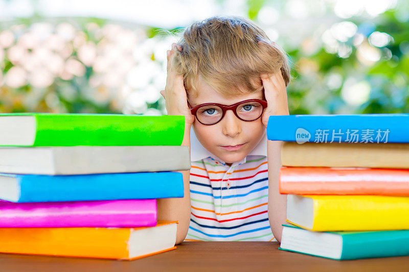 沮丧的小男孩戴着眼镜和书