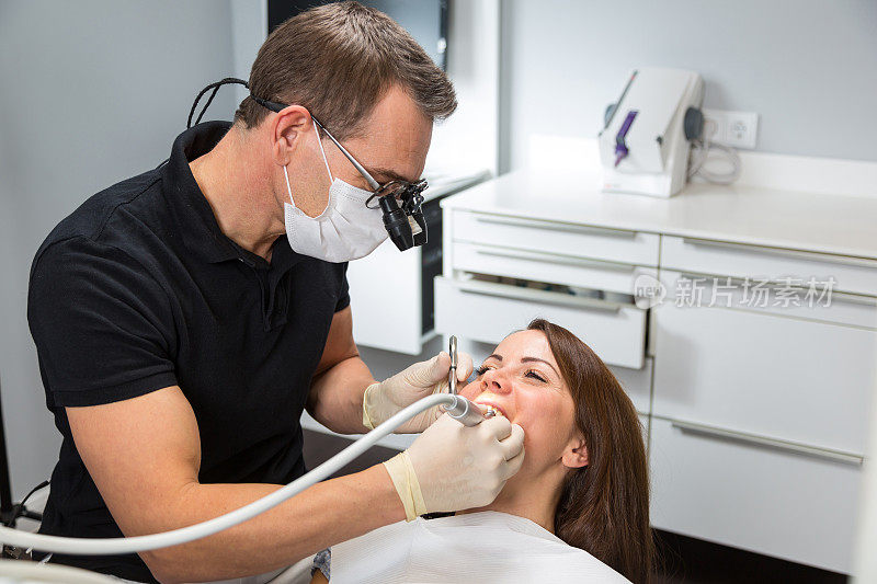 牙医在椅子上用牙钻治疗病人