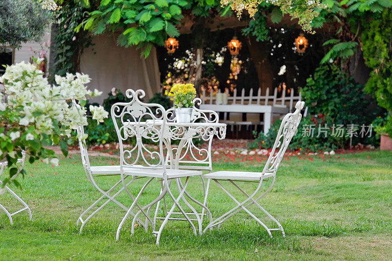 白色复古的桌子和椅子在美丽的花园。