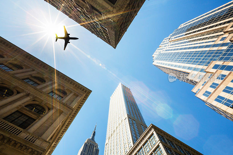 纽约市，曼哈顿摩天大楼与飞机对抗太阳