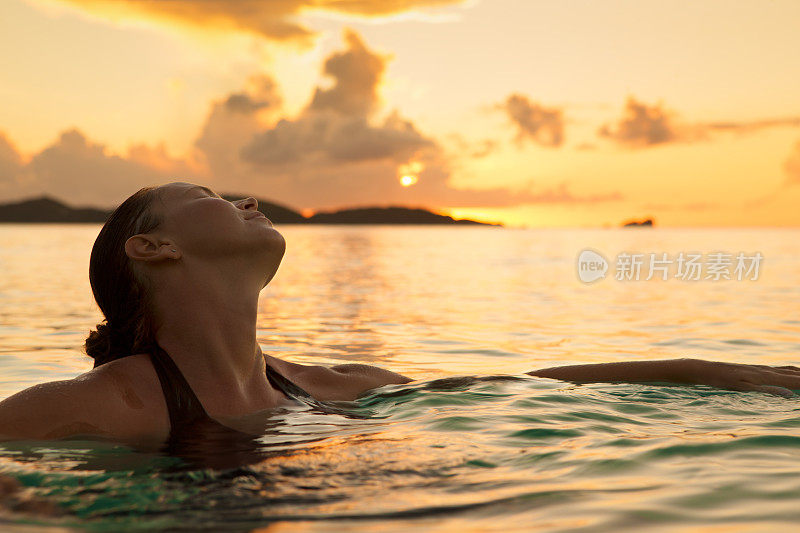 一名年轻女子在日落时分在加勒比海水域游泳