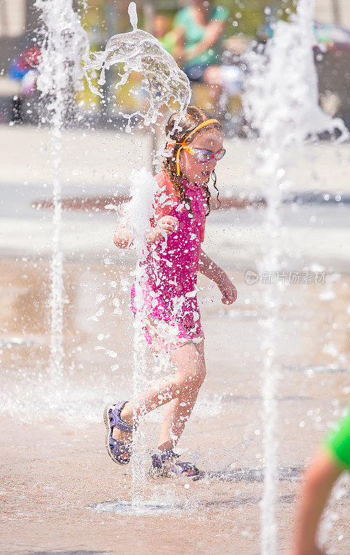 小女孩在喷泉在户外水花公园玩