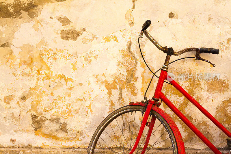 复古红色自行车，映衬着斑驳的黄色墙壁，意大利