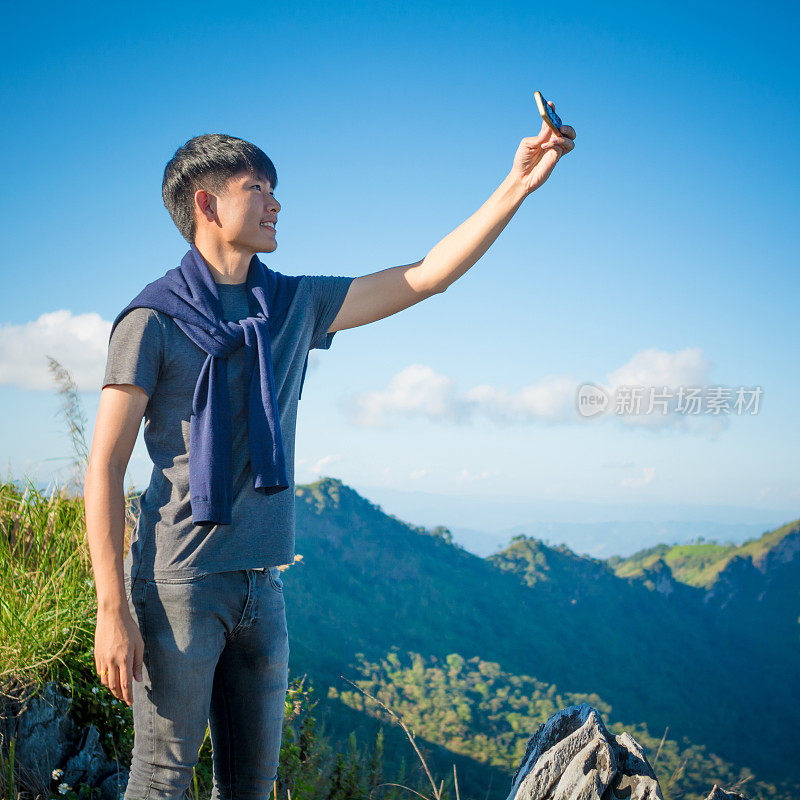 年轻的旅行者站在山上望着夕阳。