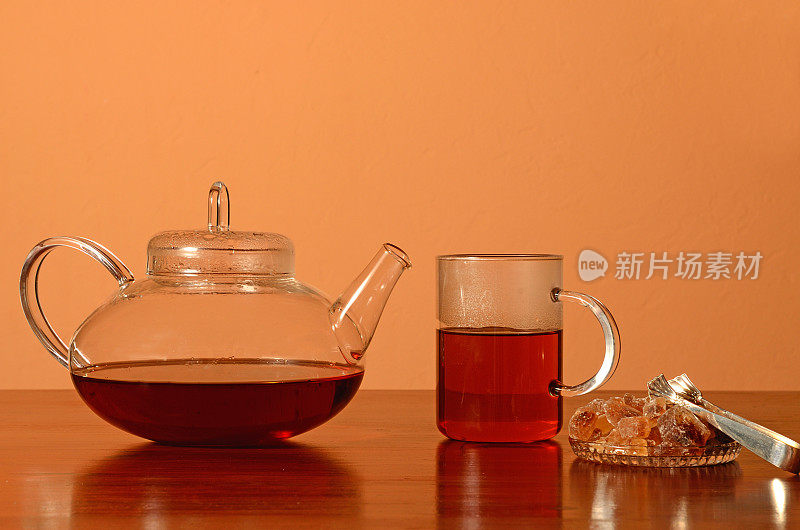 玻璃茶壶和茶杯，桌上放着棕糖