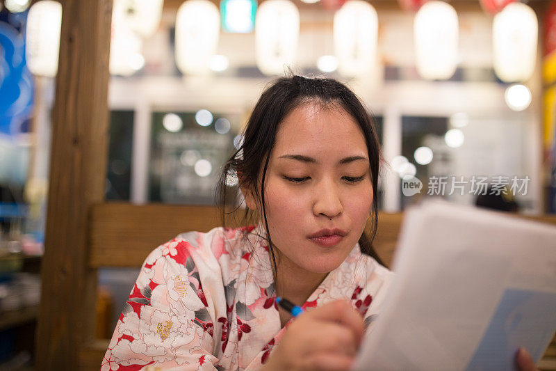 年轻的女子在日本居酒屋餐厅点东西