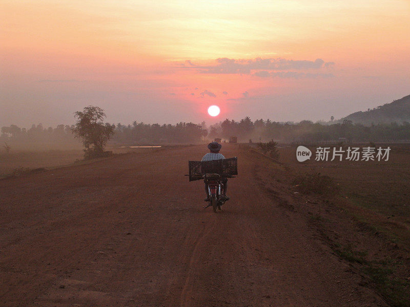 一张黎明时分一个男人骑着自行车的照片