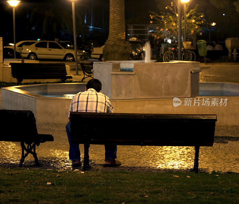 夜晚坐在城市广场上的孤独男子