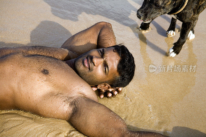 一个运动员和他的狗躺在沙滩上
