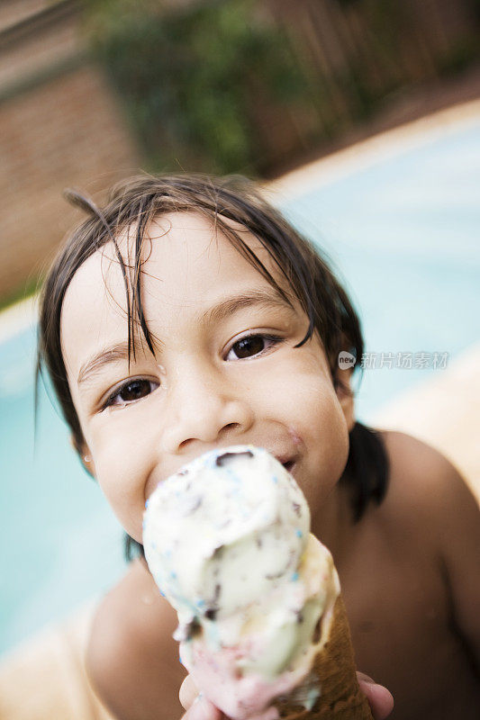 一个小男孩在泳池边吃冰淇淋的肖像
