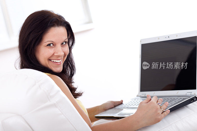 微笑的年轻女子使用笔记本电脑，在家里工作
