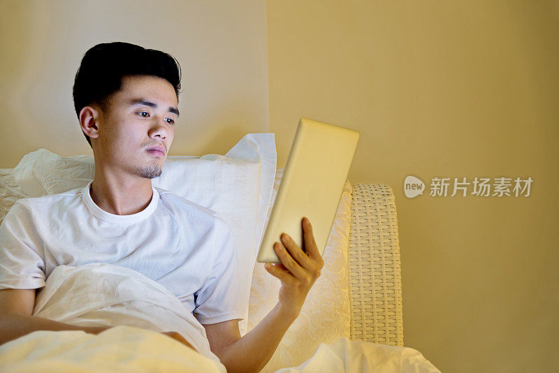 年轻人在床上用平板电脑