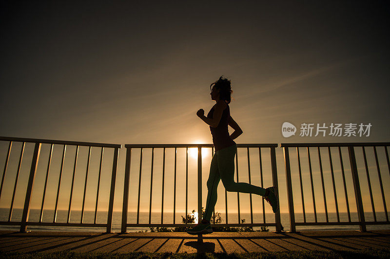 年轻女子在夕阳下奔跑的剪影