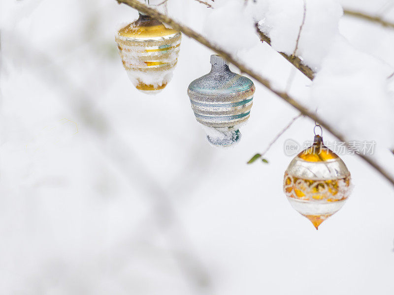 三个圣诞球在树枝上用雪做卡片