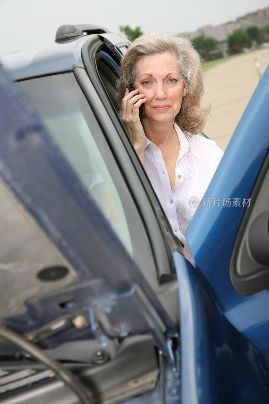 担心的成年妇女与坏掉的汽车打电话