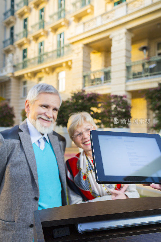 酒店接待员用平板电脑迎接老夫妇