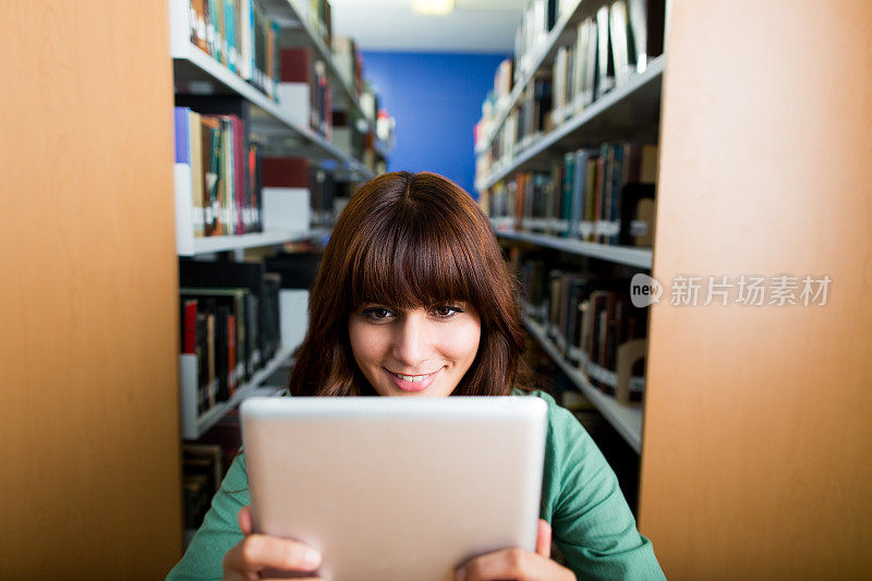 漂亮年轻的大学生从平板电脑上阅读