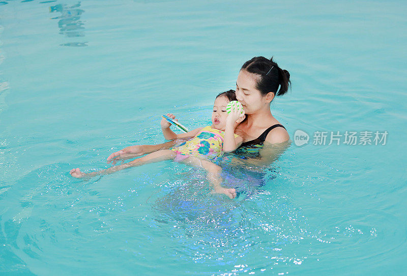 母亲在游泳池里教孩子的家庭。