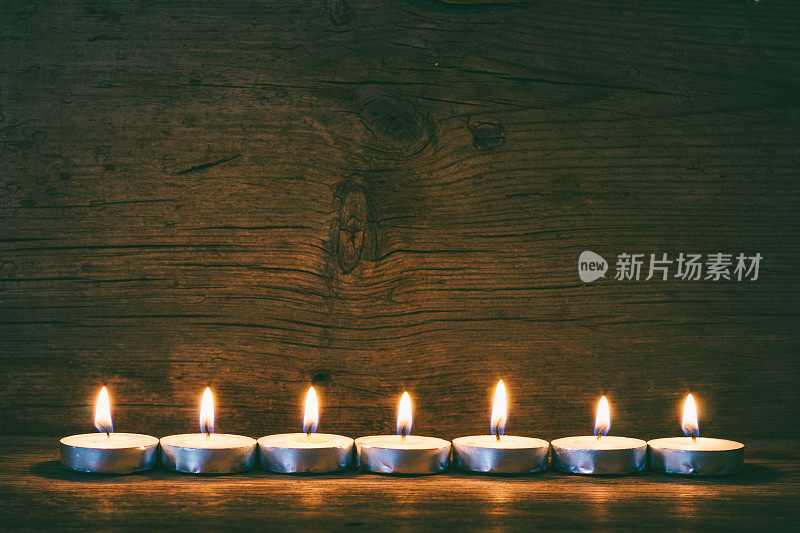 燃着的蜡烛在旧谷仓板的背景上，着色的照片
