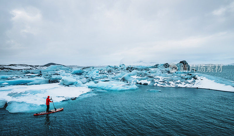 美丽的冰山冰川泻湖与一个家伙桨登(sup)，全球变暖和气候变化的概念