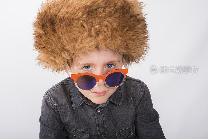 戴着皮草帽子的小男孩从眼镜边往外看。