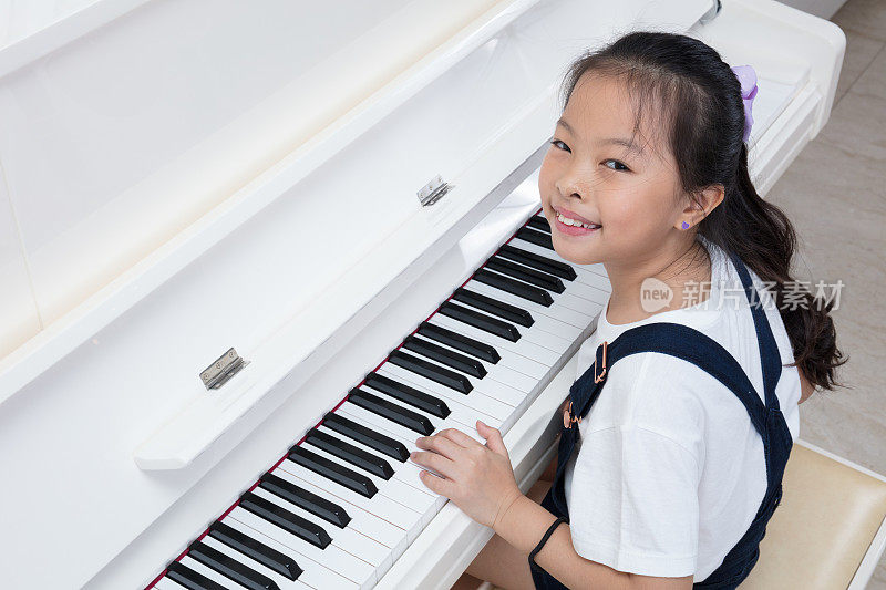 快乐的亚洲华人小女孩在家里弹奏古典钢琴