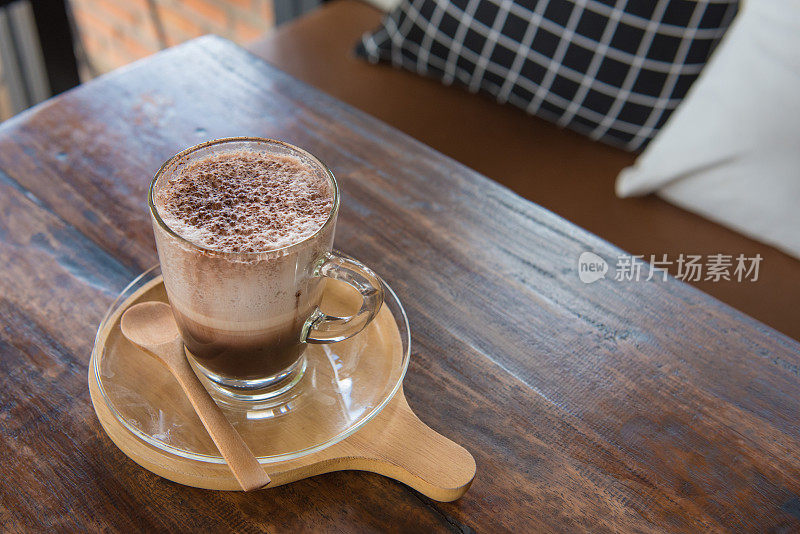 桌上的木托盘上放着一杯清亮的热巧克力和白奶油。