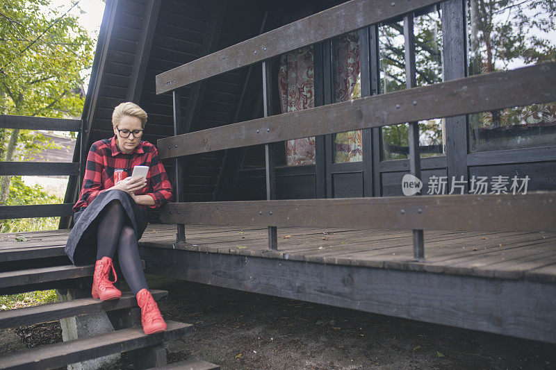 可爱的女孩在老房子前用手机。