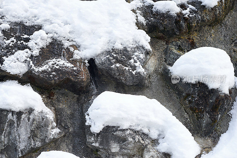 垂直的山坡上有被雪覆盖的岩石