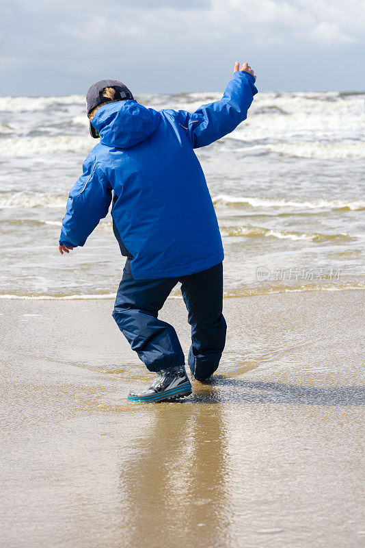 男孩穿着防水衣服在海滩上