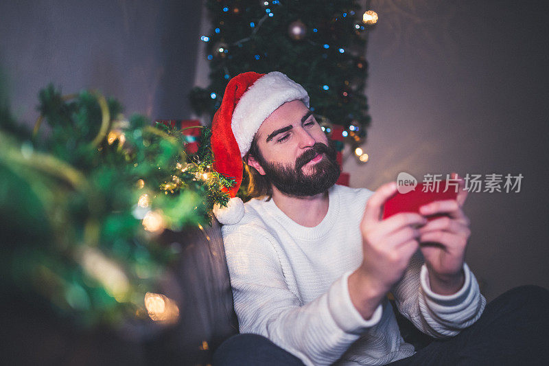 英俊的男人戴着圣诞帽在平安夜使用手机