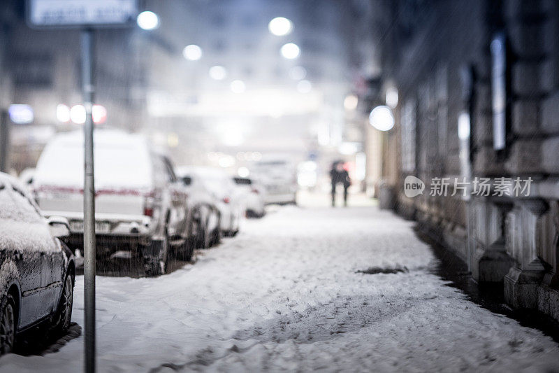 寒冷冬夜的人行道，汽车被雪覆盖