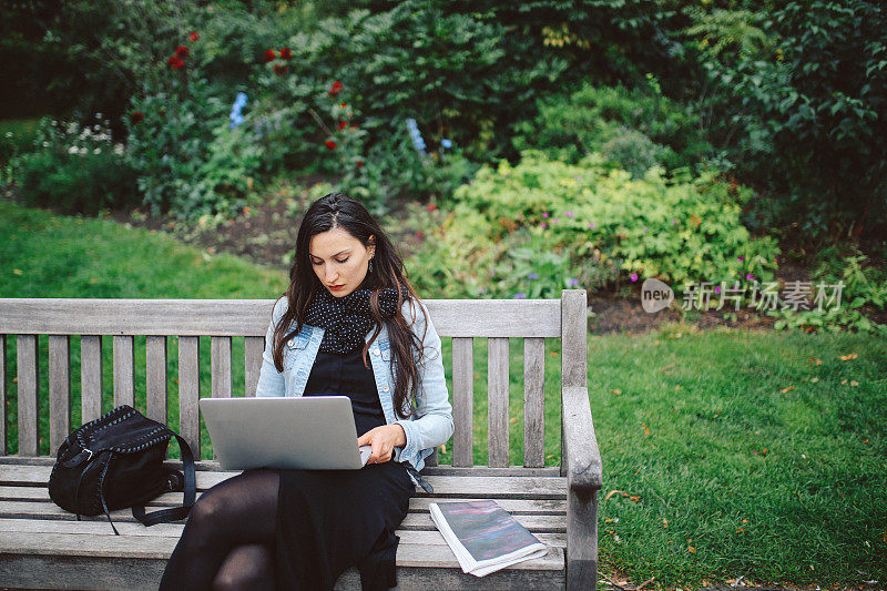 在伦敦公共公园用笔记本电脑工作的黑发女人