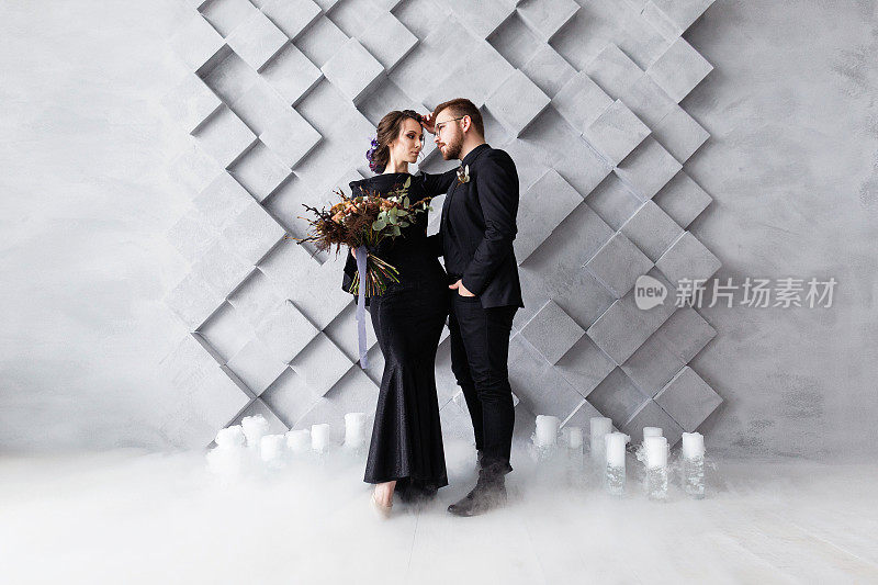 婚礼夫妇，新娘和新郎时尚肖像，在灰色的体积背景与copyspace。干冰烟雾。