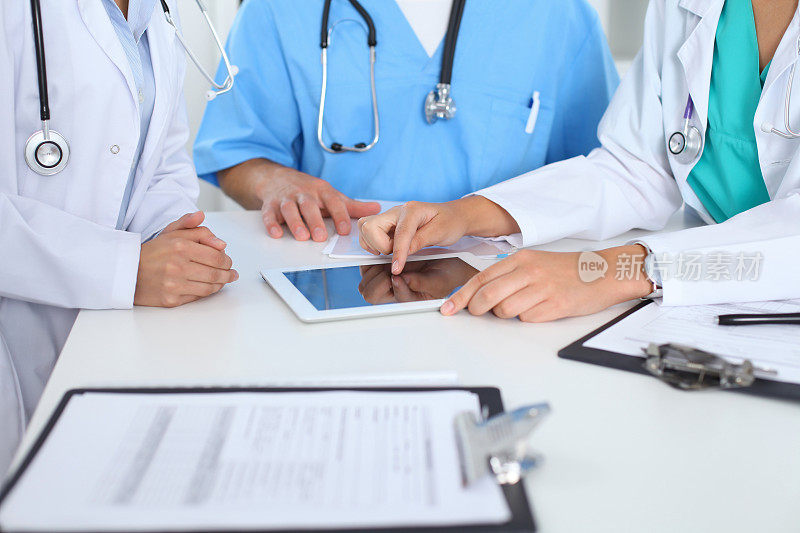 一群医生在开医学会议。医生使用触摸板或平板电脑的特写