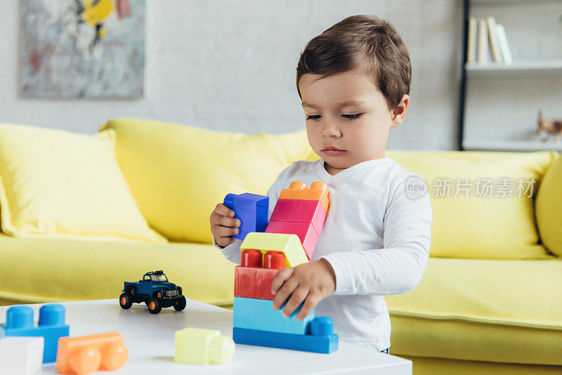 小男孩在家里玩五颜六色的积木和玩具车