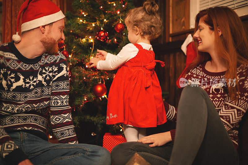 年轻的家庭和小女孩装饰圣诞树