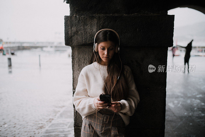 在城市里戴着耳机的年轻女子