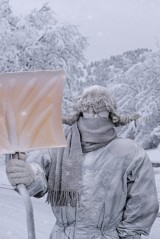 冻僵的人拿着雪铲在户外的雪地里