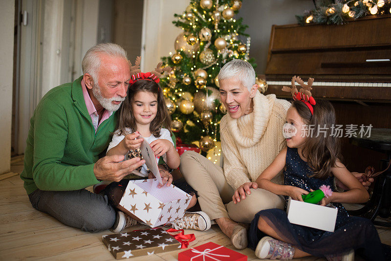 一对老夫妇在帮孙子孙女打开圣诞礼物