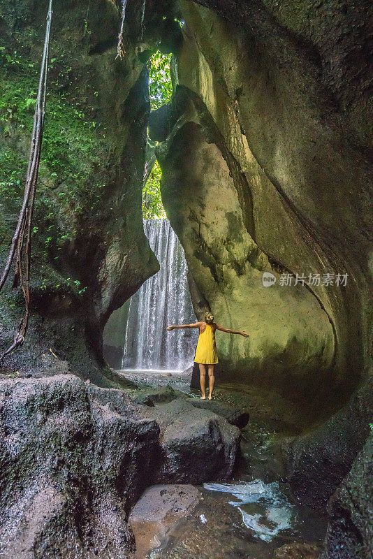 在巴厘岛的热带雨林中，旅行的年轻女子张开双臂拥抱大自然的美丽。人们以自然为旅游理念。