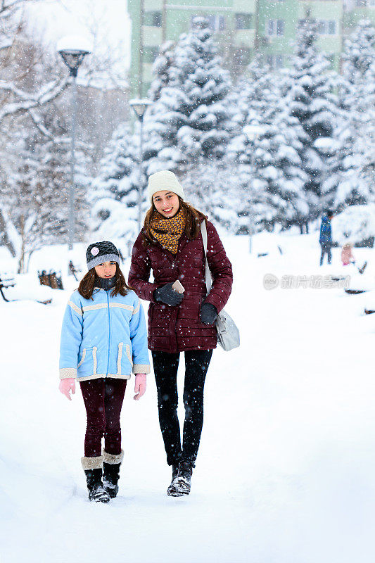 两姐妹走在白雪覆盖的森林里