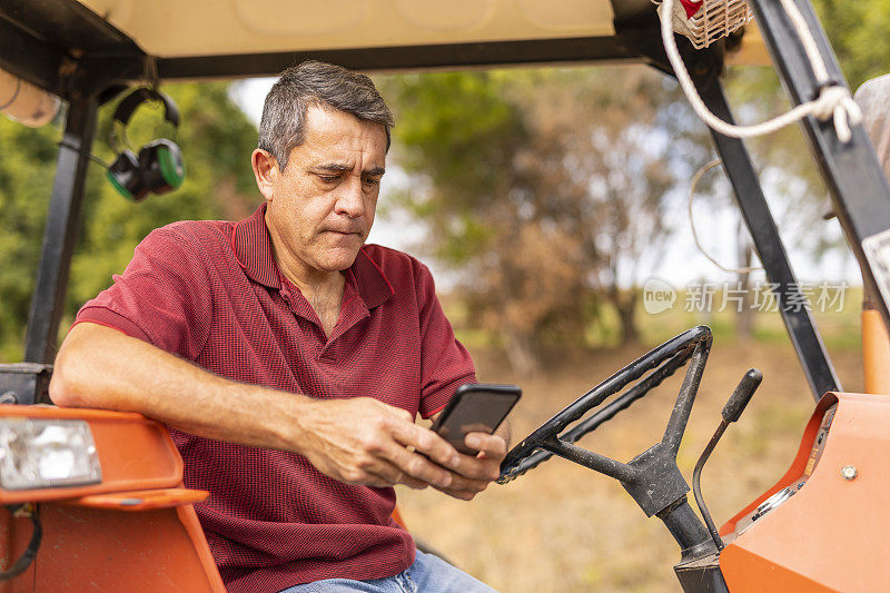 中年农民在拖拉机上使用手机