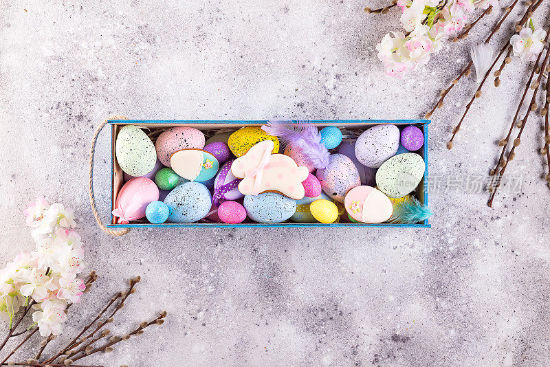 复活节彩绘彩蛋和彩釉饼干兔子用稻草窝在木箱石背景上，庆祝新春佳节，复制空间