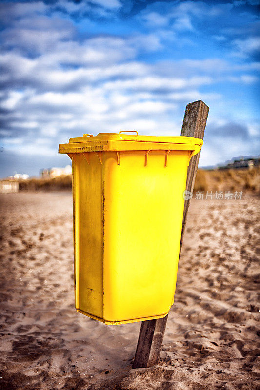 海滩上的黄色废物容器