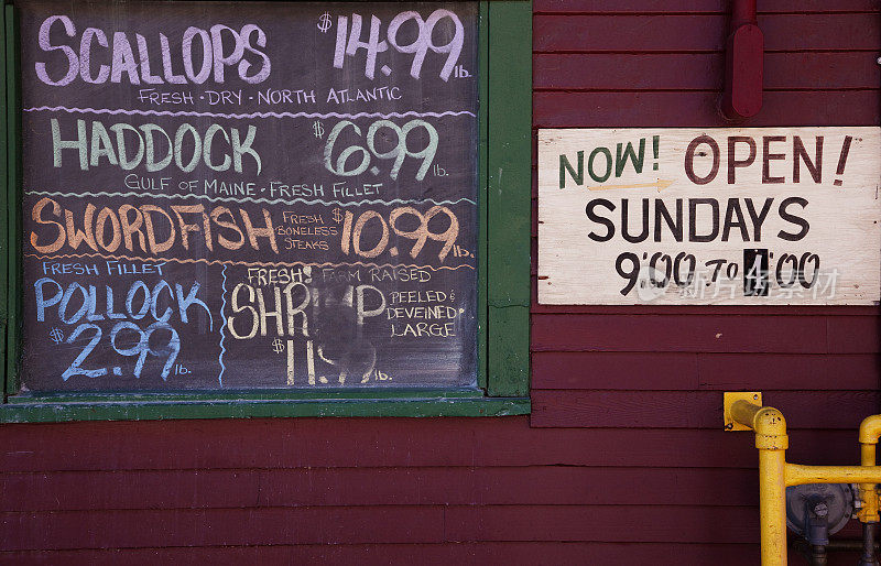 缅因州波特兰市海鲜市场，黑板上写着鱼的价格和市场工作时间