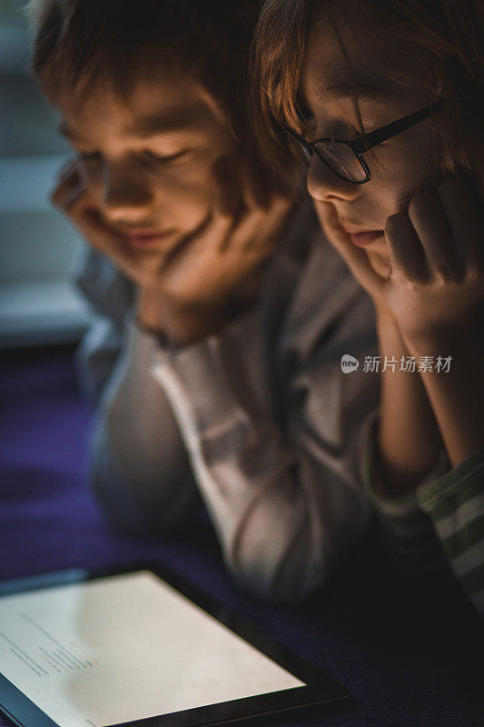 十几岁的男孩在放松和一起使用数字平板电脑的时候集中注意力
